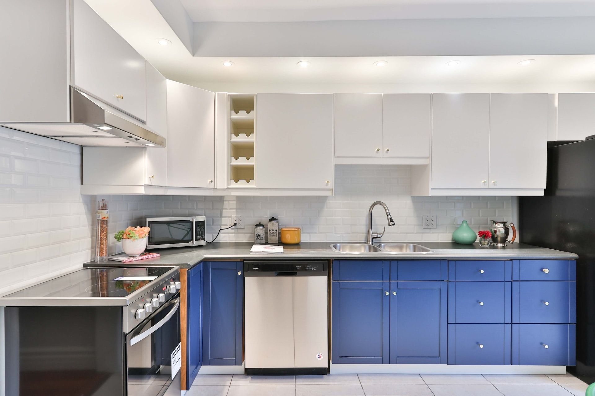 Modern fitted kitchen in Newcastle upon Tyne with white wall units, navy base units and a tiled splashback