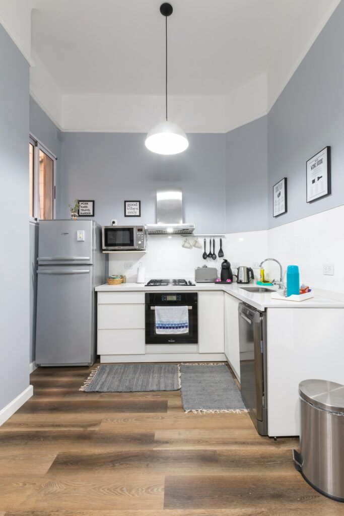 Newcastle Kitchen Fitters: compact fitted kitchen with white units, grey walls and wood-effect flooring